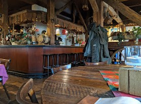 An old-fashioned tavern with wooden furniture and a cluttered bar.